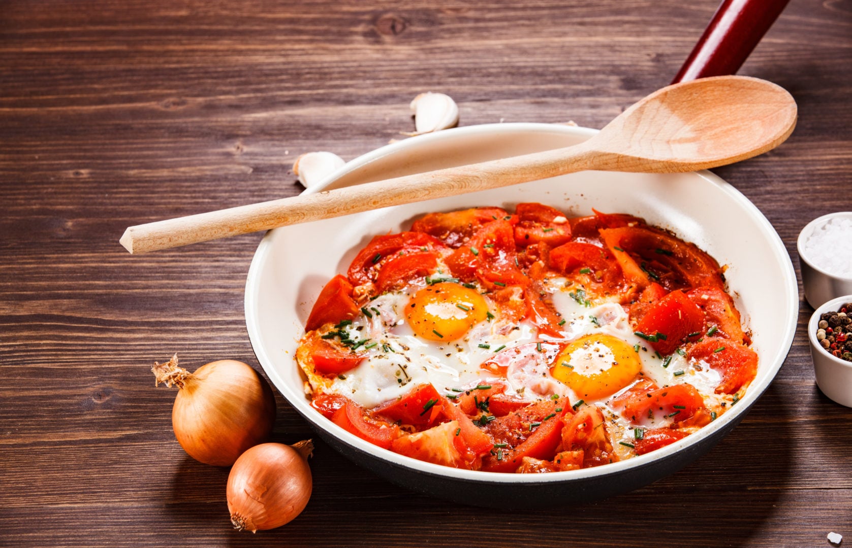 Shakshuka - fried eggs with vegetables in frying pan